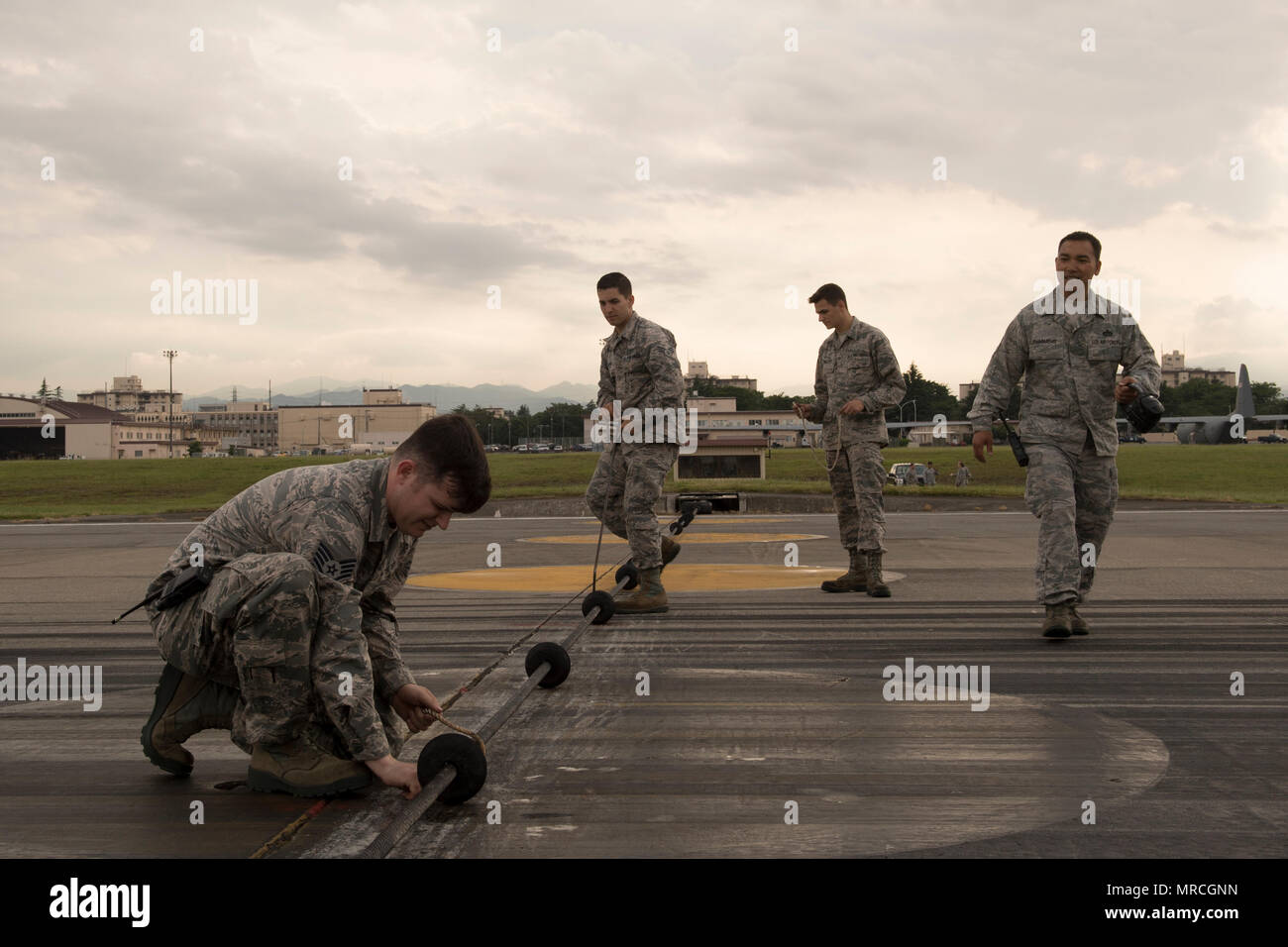 Airmen with the 374th Civil Engineer Squadron power productions shop inspect an emergency aircraft landing cable on the runway at Yokota Air Base, Japan, June 1, 2017, during an annual certification test of Aircraft Arresting System. Testing the system on an annual basis is the responsibility of the 374 CES and 374th Operations Support Squadron airfield management. (U.S. Air Force photo by Yasuo Osakabe) Stock Photo