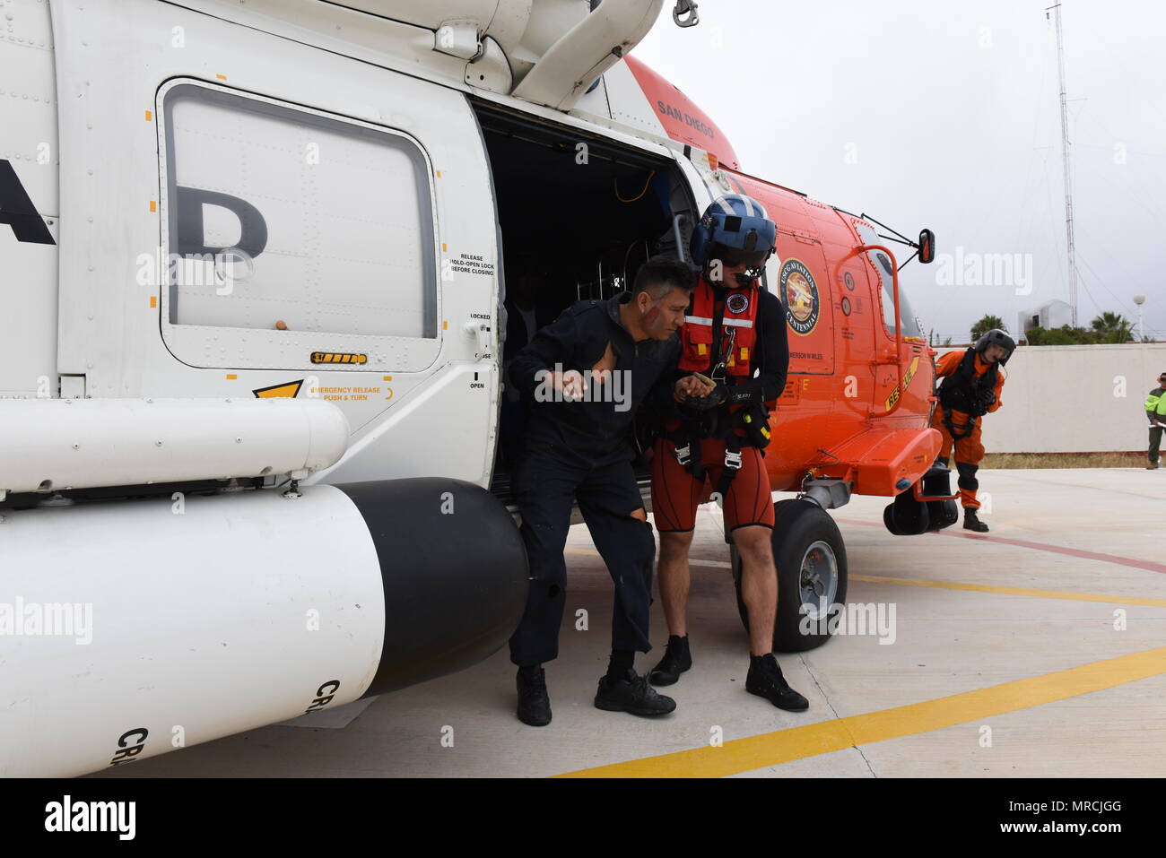 Petty Officer 2nd Class Lyman Dickinson, an aviation survival technician at Coast Guard Sector San Diego, assists a simulated survivor out of an MH-60 Jayhawk helicopter during a joint search and rescue exercise with the Mexican navy in Ensenada, Mexico on June 7, 2017. The exercise simulated a vessel fire off the coast that required a coordinated international search and rescue effort. (U.S. Coast Guard photo by Petty Officer 3rd Class Joel Guzman) Stock Photo