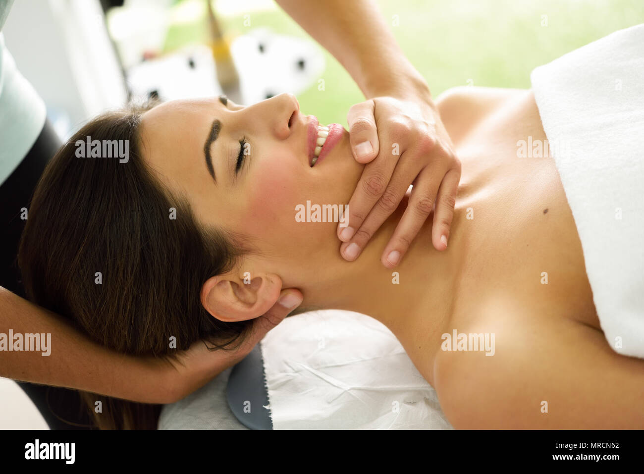 Young caucasian smiling woman receiving a head massage in a spa center with eyes closed. Female patient is receiving treatment by professional therapi Stock Photo