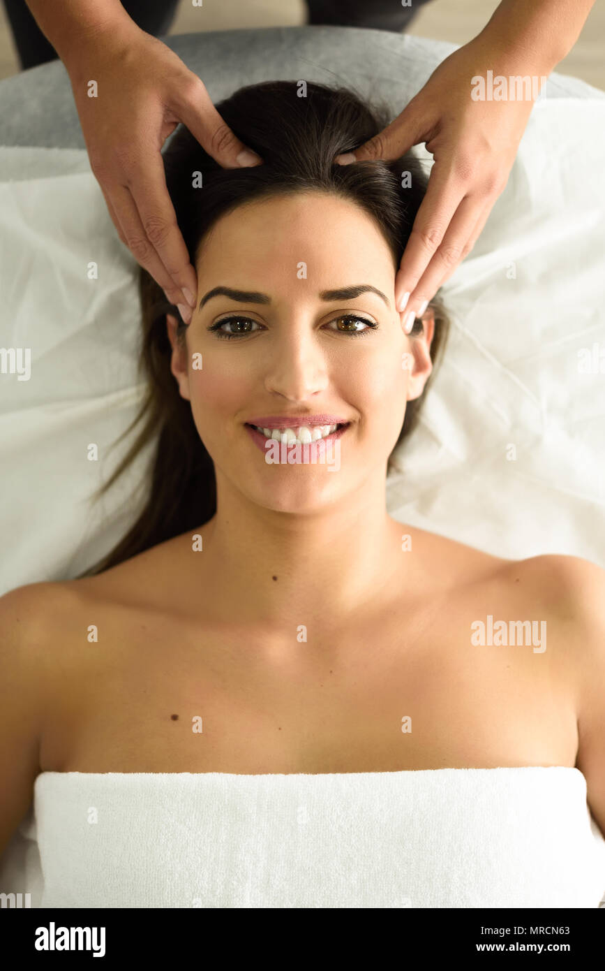 Top view of young caucasian smiling woman receiving a head massage in a spa center. Female patient is receiving treatment by professional therapist. Stock Photo