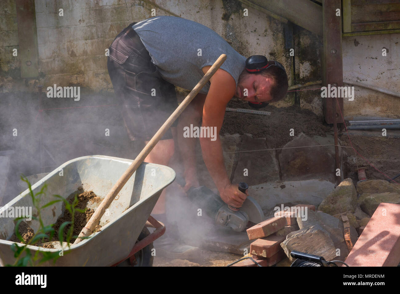 Worker cuts the bricks with a cut-off grinder. Stock Photo