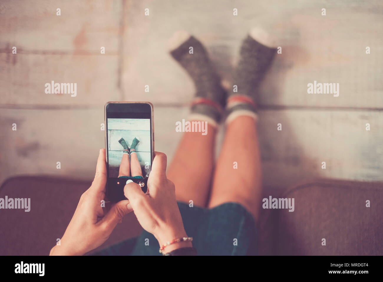 beautiful caucasian woman take picture with mobile phone at her legs against the wall with nice and funny socks. home alternative lifestyle and indepe Stock Photo