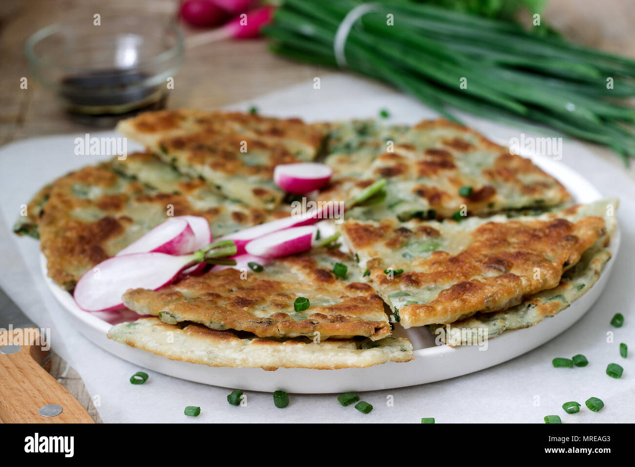 Homemade appetizing scallion pancakes with a bunch of green onions and radishes. Rustic style. Stock Photo