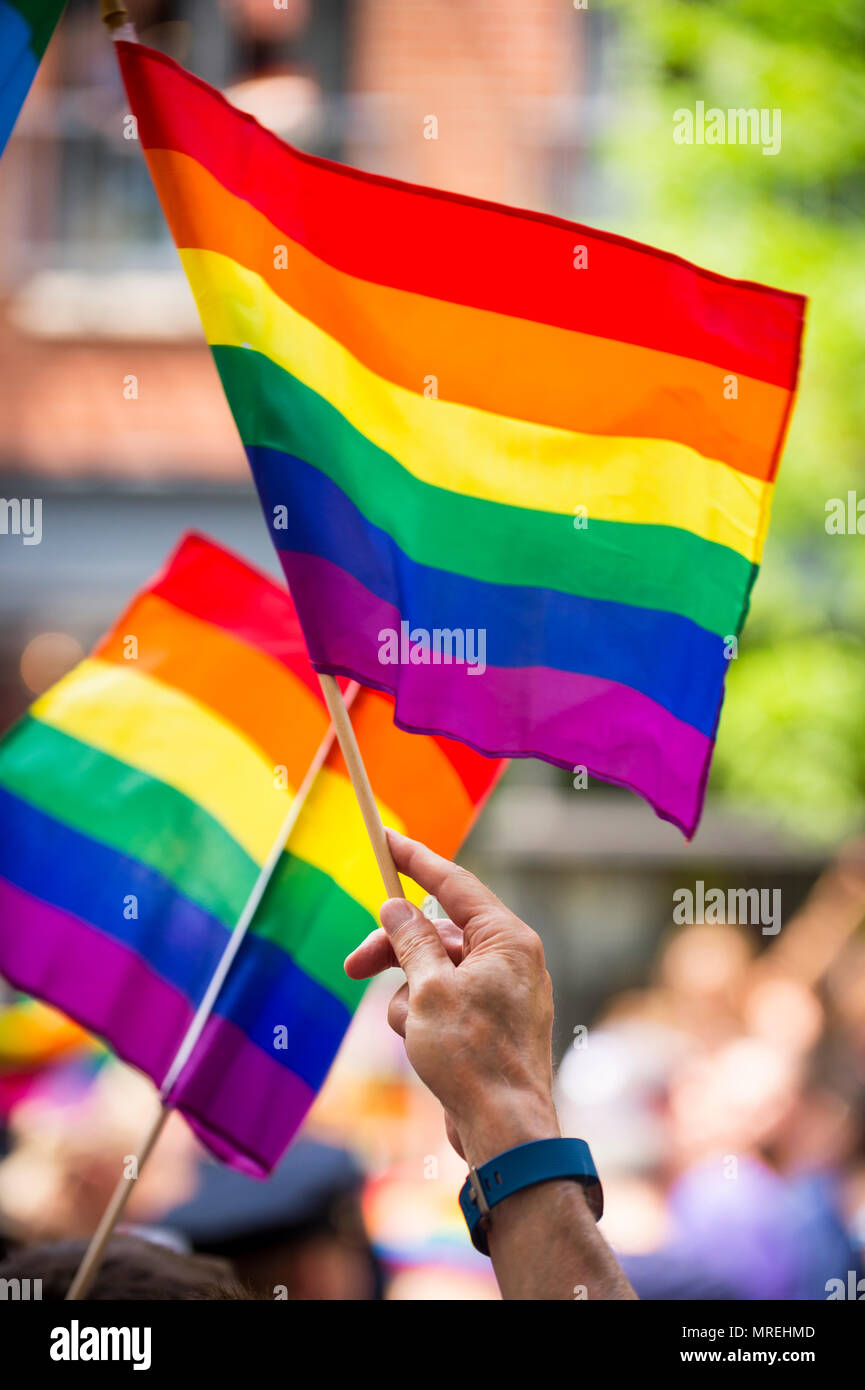 Rainbow flags flying in bright sun on the sidelines of a colorful summer gay pride parade Stock Photo