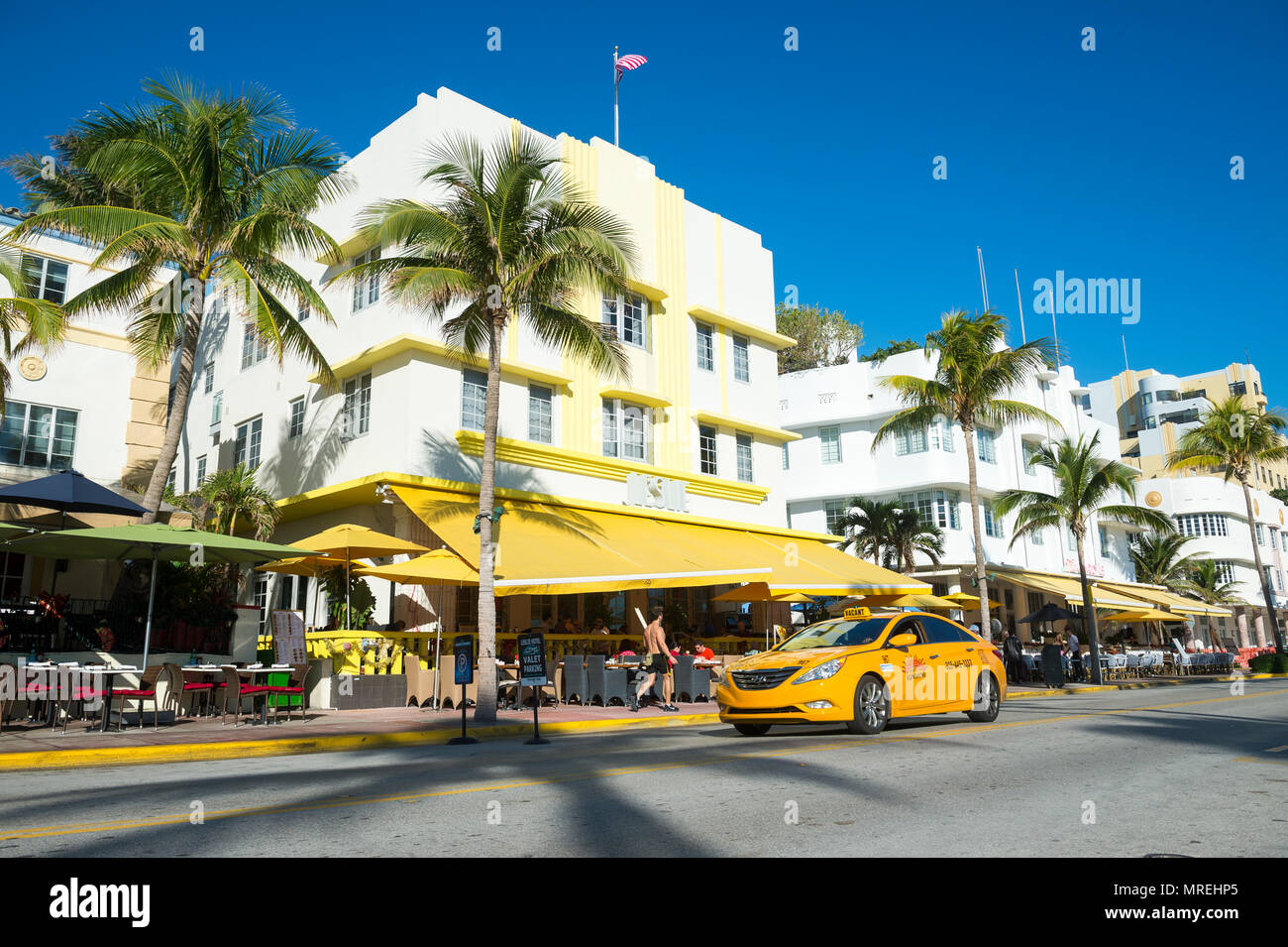 MIAMI - JANUARY 12, 2018: Restaurants on the tourist strip of Ocean Drive stand ready for morning customers in South Beaches a taxi drives past. Stock Photo