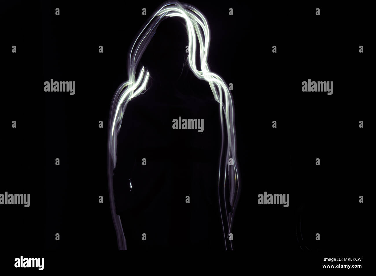 A silhouette of a girl on a black background. Glow white-purple line is around her. Stock Photo