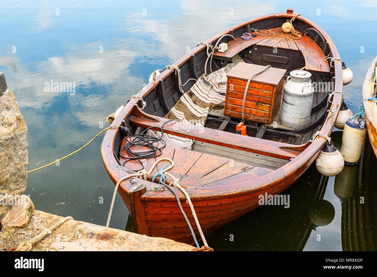Wooden vintage motorboat moored in windless water on a sunny day. Stock Photo