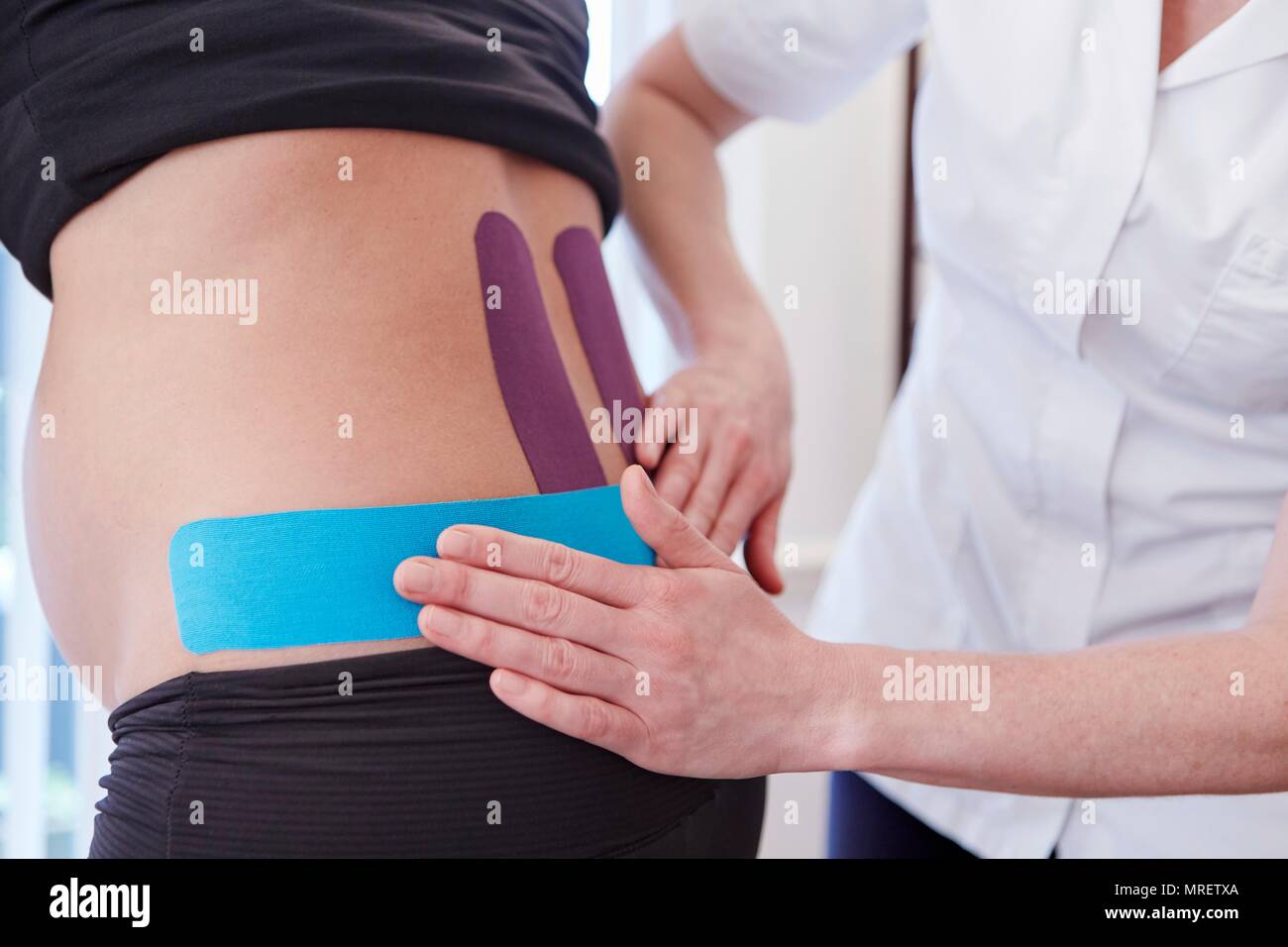 Osteopath applying tape to pregnant patient. Stock Photo