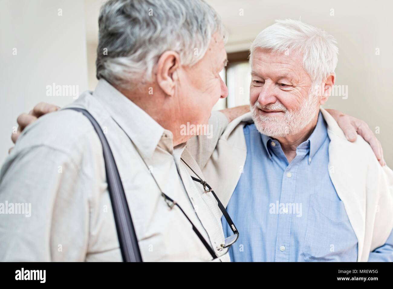 Two senior men in care home with arms around each other. Stock Photo