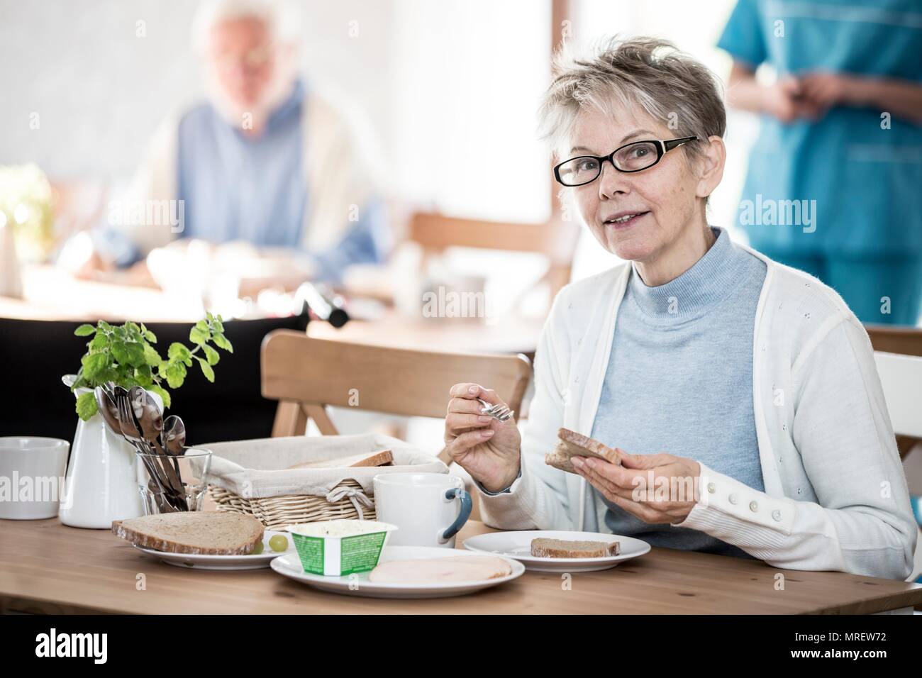 Senior woman eating meal in care home. Stock Photo