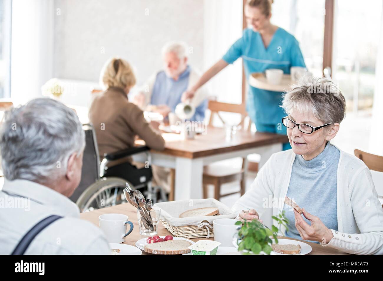 Senior adults eating meal in care home. Stock Photo