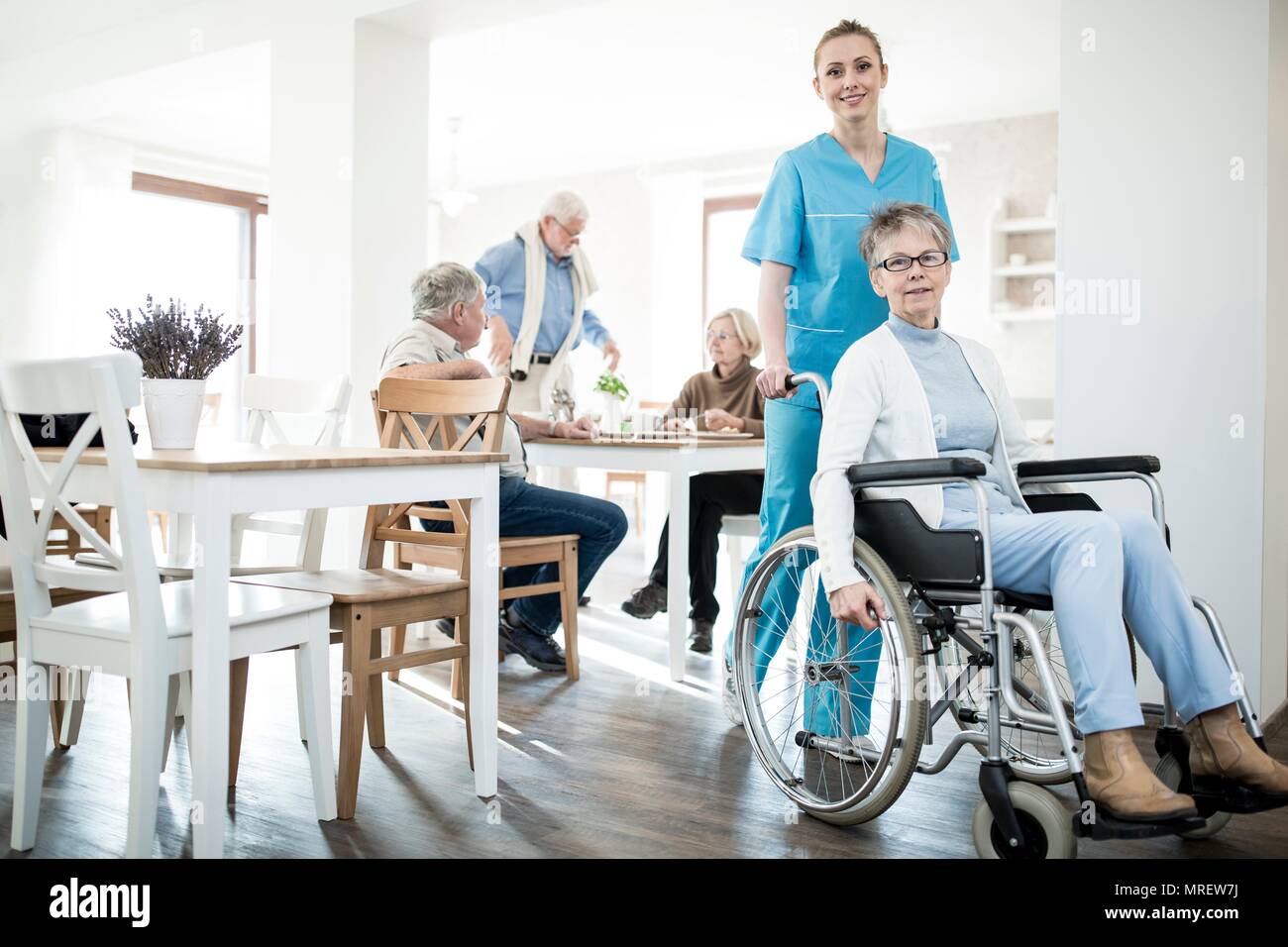 Senior woman in wheelchair with care worker in care home. Stock Photo