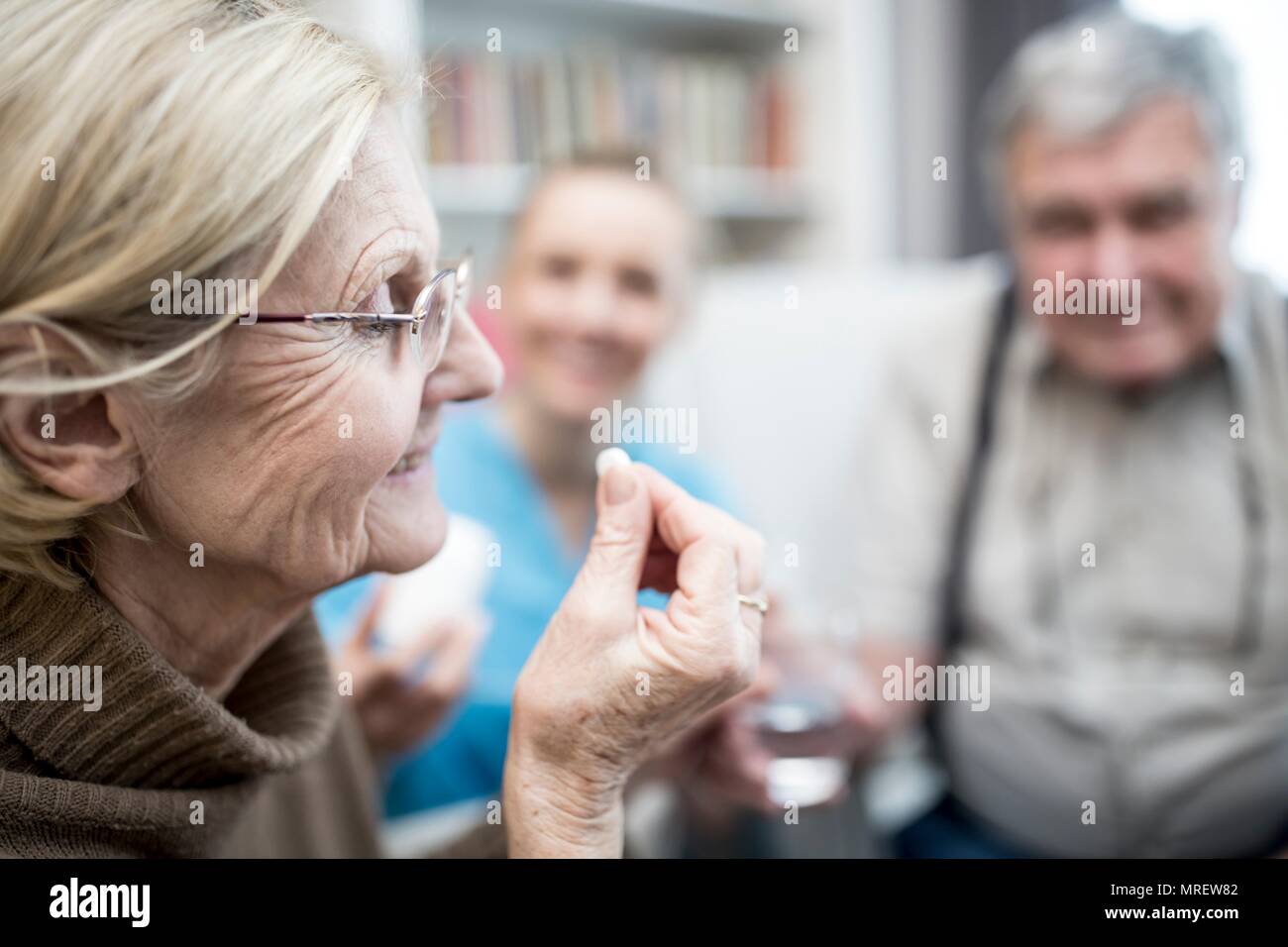 Senior woman taking tablet in care home. Stock Photo