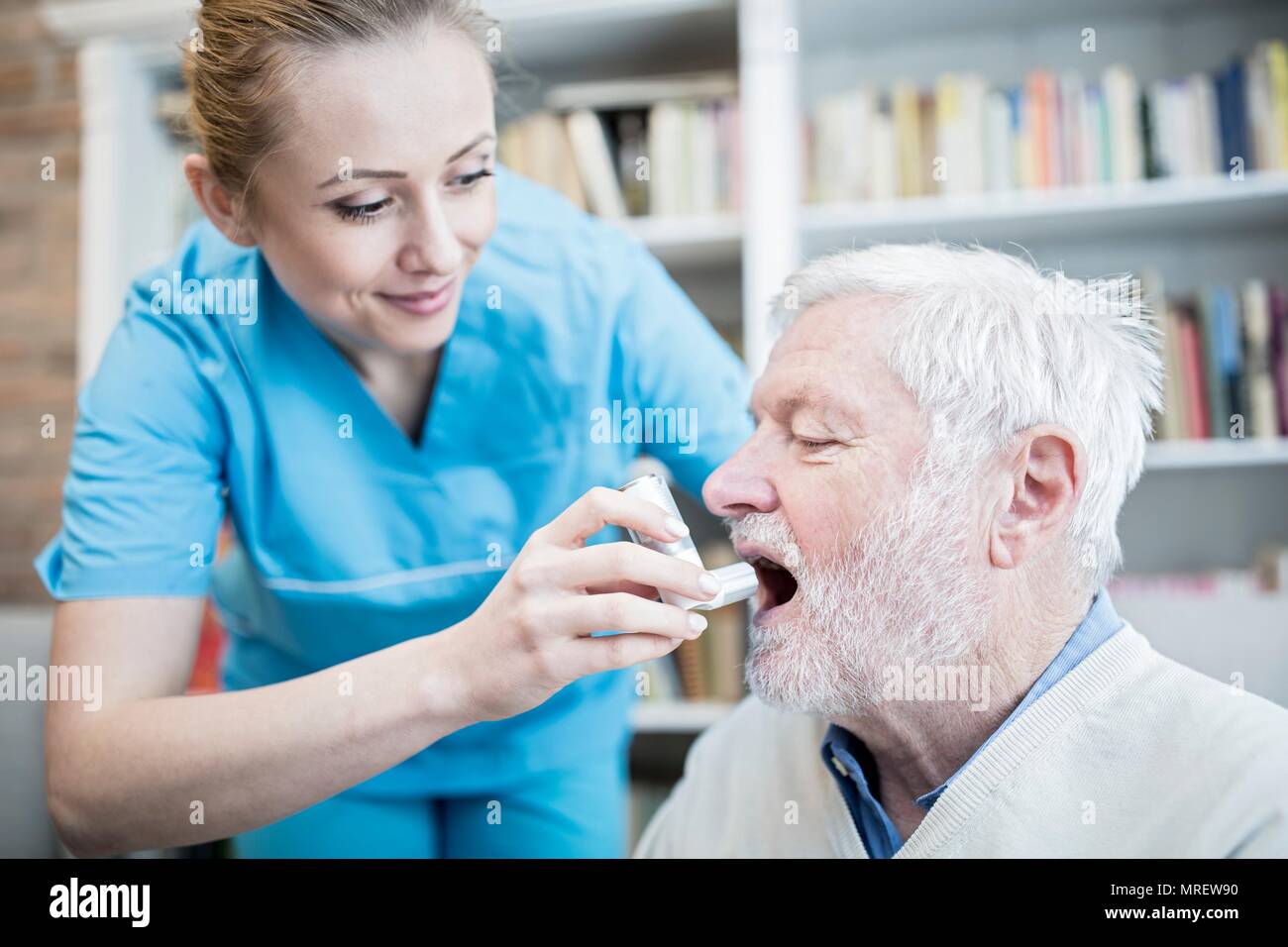 Care worker helping senior man with inhaler. Stock Photo