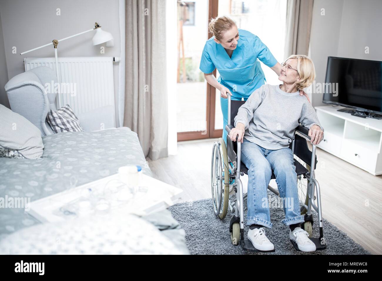 Senior woman in wheelchair with care worker in care home. Stock Photo