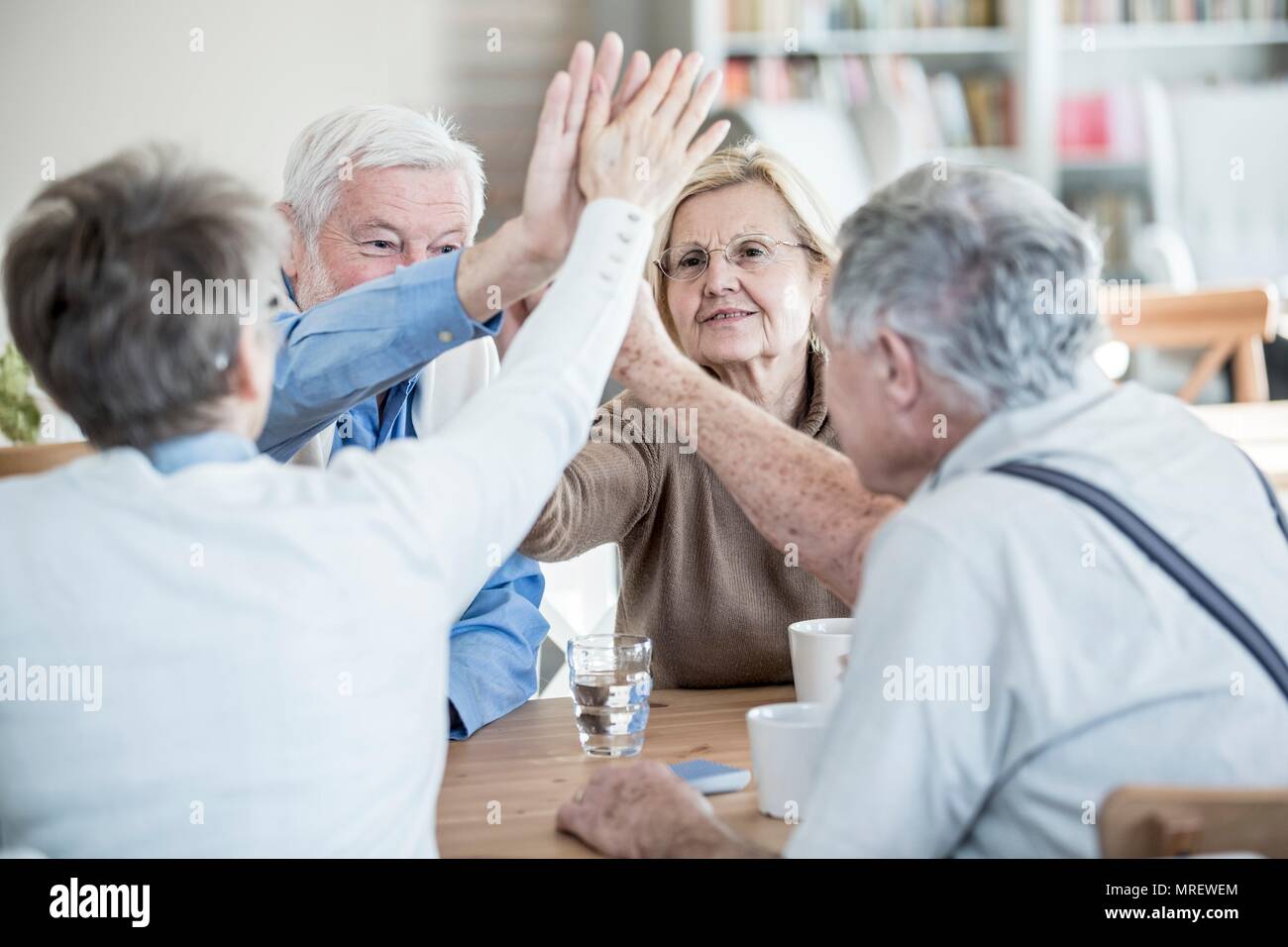 Friends giving high fives in retirement home. Stock Photo