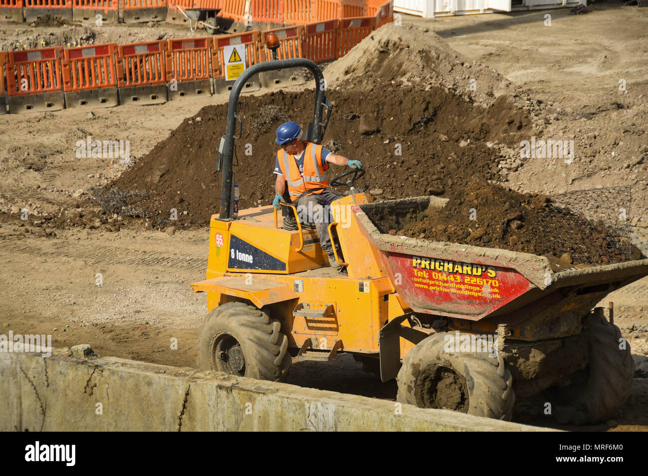 Construction worker driving a dumper full of earth on the site of a new office development in Pontypridd town centre Stock Photo