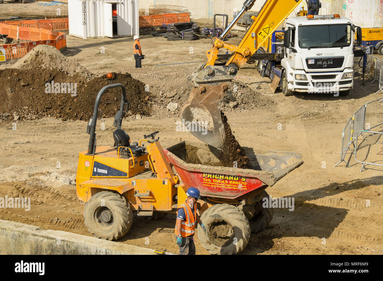 JCB excavator at work loading a dumper with earth on the site of a new office development in Pontypridd town centre Stock Photo