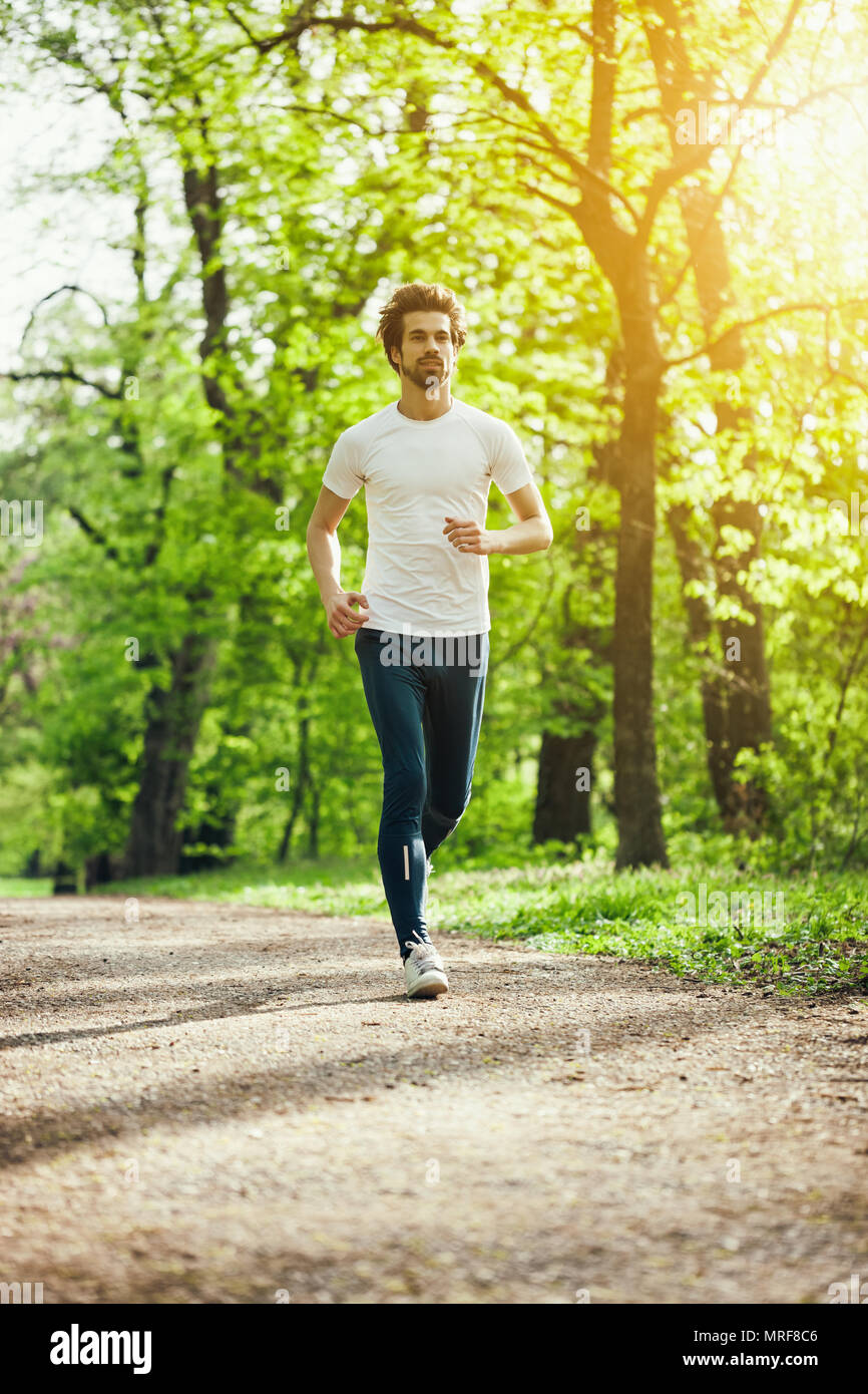 Young man is jogging in park. Stock Photo