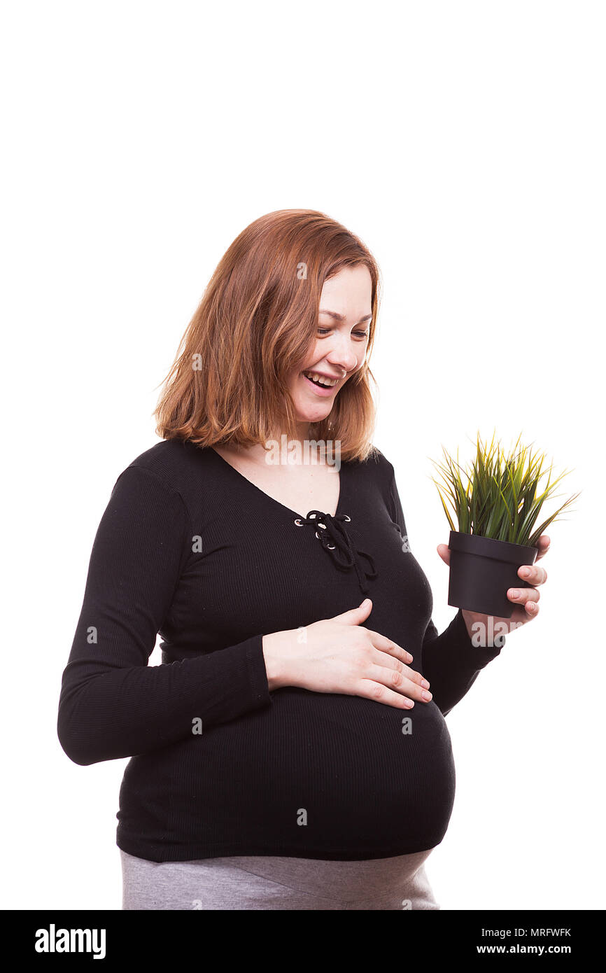 beautiful pregnant woman holds a pot with grass in her hands