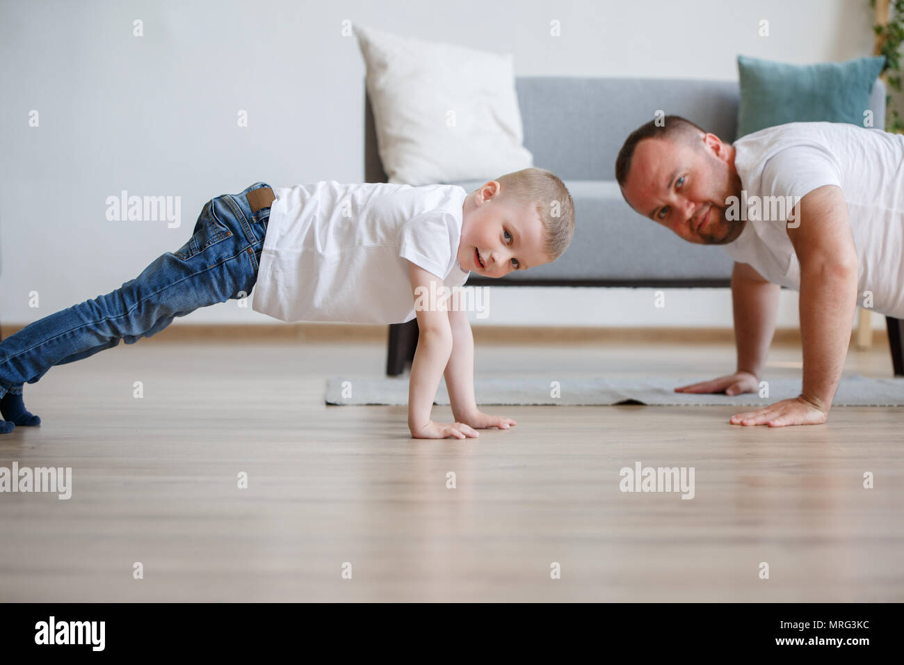Photo Of Young Father And Son Pushing Up On Floor Against Sofa
