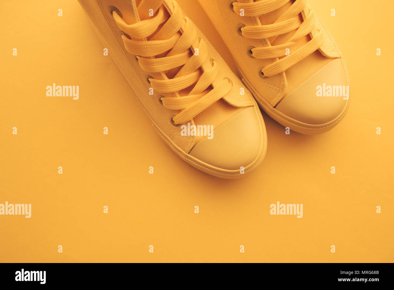 Sneaker shoes for youth lifestyle concept, pastel toned yellow footwear with copy space, top view Stock Photo