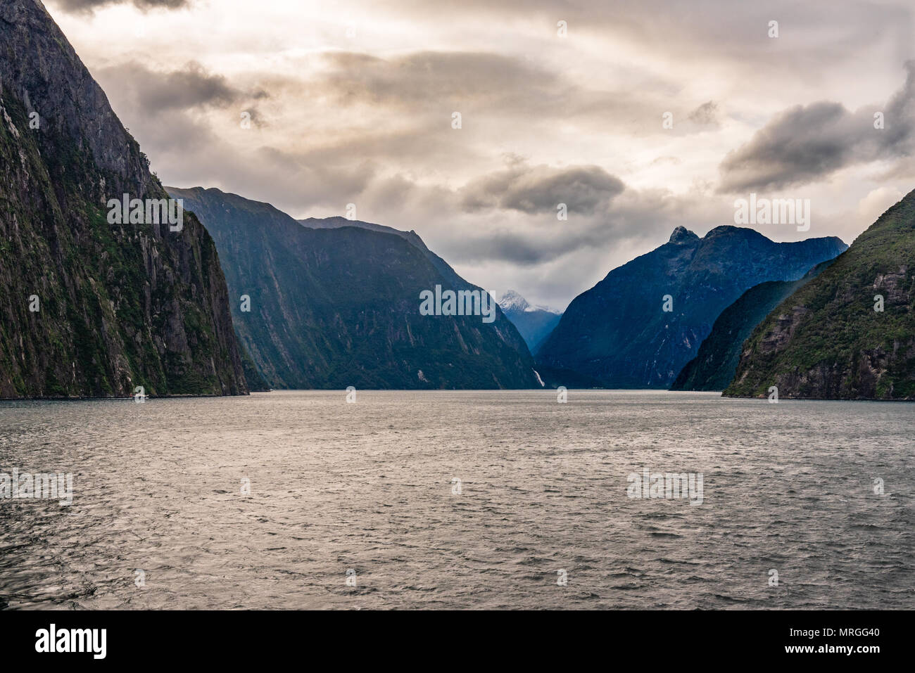 A dark and narrow passageway through a New Zealand Fiord under threatening skies. Stock Photo