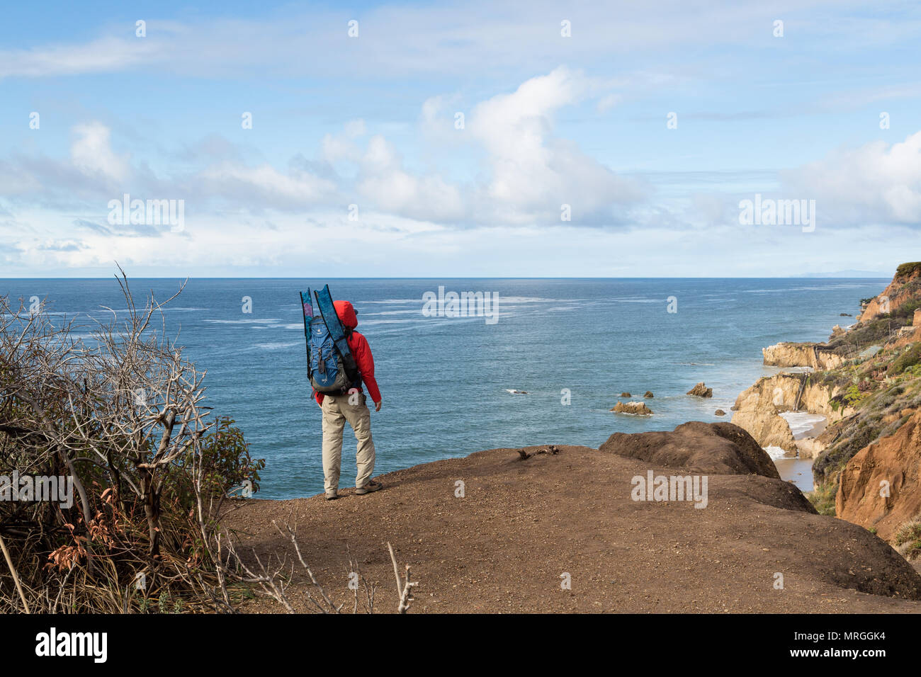 A freediver wearing a backpack ready for adventure stares out at the ocean from El Matador State Beach in Malibu, California. Stock Photo