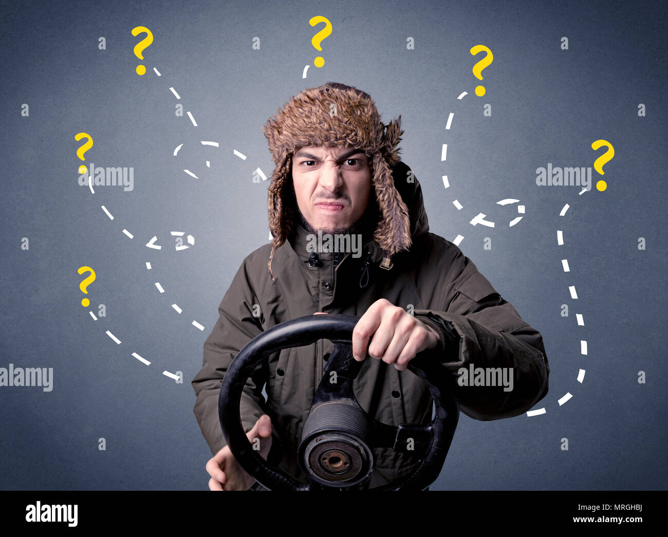 Young man holding black steering wheel with question marks around him