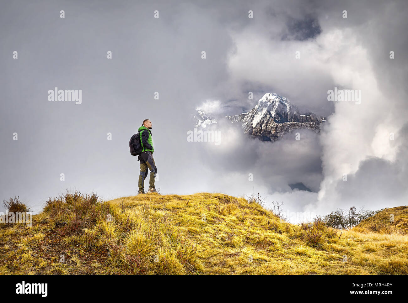 Tourist with backpack enjoying the view of snowy Himalayan Mountain at cloudy sky in Nepal Stock Photo
