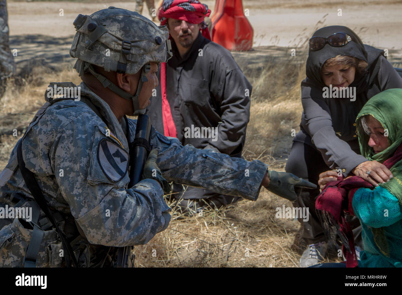 U.S. Army Staff Sgt. Eric Manalansan, 491st Military Police Company out of Riverside, Calif., assesses injuries on Ms. Rebecca Riel, computer illustrator from Lockwood, Calif., while she is role playing as a local villager in their training exercise during the 91st Training Division’s Warrior Exercise (WAREX) 91-17-03 on Fort Hunter Liggett, Calif. on June 15, 2017. Their training scenario involved providing medical aid for local villagers entering their Tactical Assembly Area, this is to prepare them for similar encounters they may face while deployed overseas. (U.S. Army photo by Spc. Sean M Stock Photo