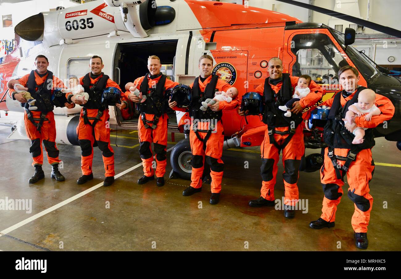 Coast Guard Sector Columbia River MH-60 Jayhawk helicopter pilots Lt. Patrick Wright, Lt. j.g. Jason Weeks, Lt. Cmdr. James Cooley, Ensign Dave Strojny, Lt. Kyle Murphy and Lt. Jonathan Ralston hold their babies during a gathering at the base hangar in Warrenton, Ore., June 13, 2017.    Each of the aviators have welcomed a new child into the Coast Guard family within the last 5 months.    U.S. Coast Guard photo by Petty Officer 1st Class Levi Read. Stock Photo