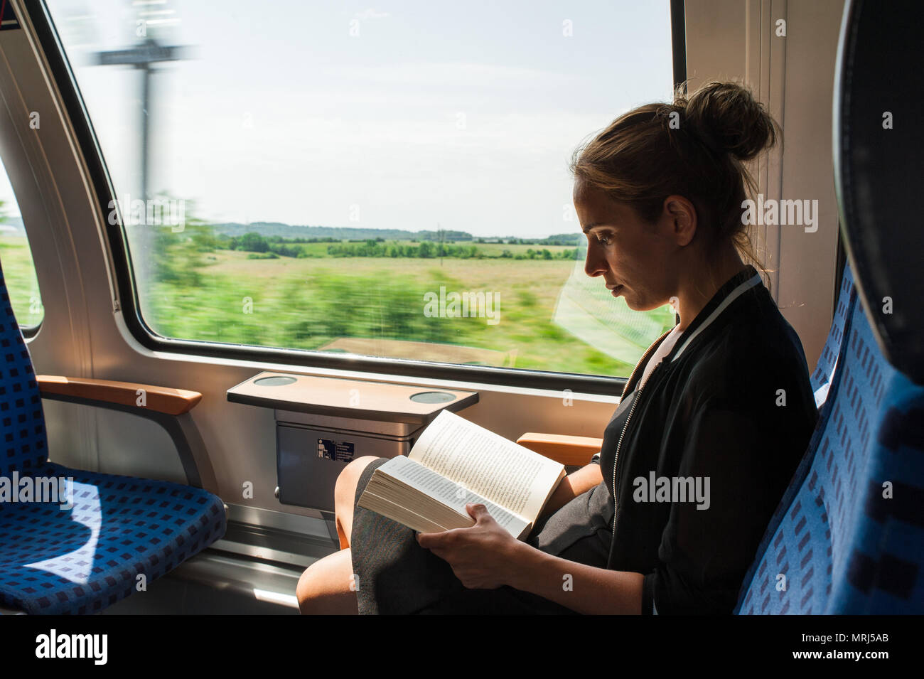 Young woman reading a book while travelling by train Stock Photo