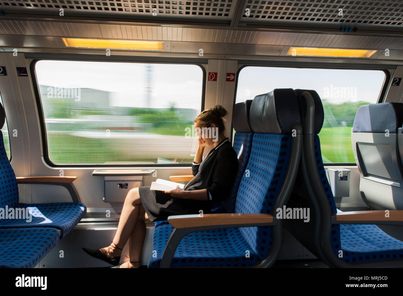 Young woman reading a book while travelling by train Stock Photo