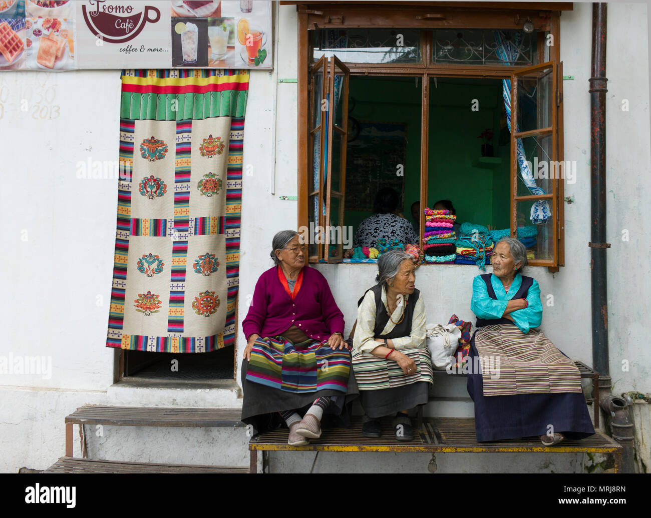 Three old Tibetan women in traditional clothes sitting in conversation in Mcleoudganj, Dharmsala, India Stock Photo