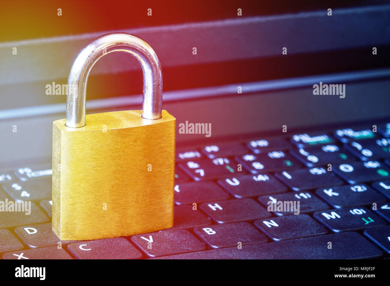 Golden padlock on computer laptop keyboard with sunflare effect and copy space. Concept of Internet security, data privacy, cybercrime prevention. Sel Stock Photo