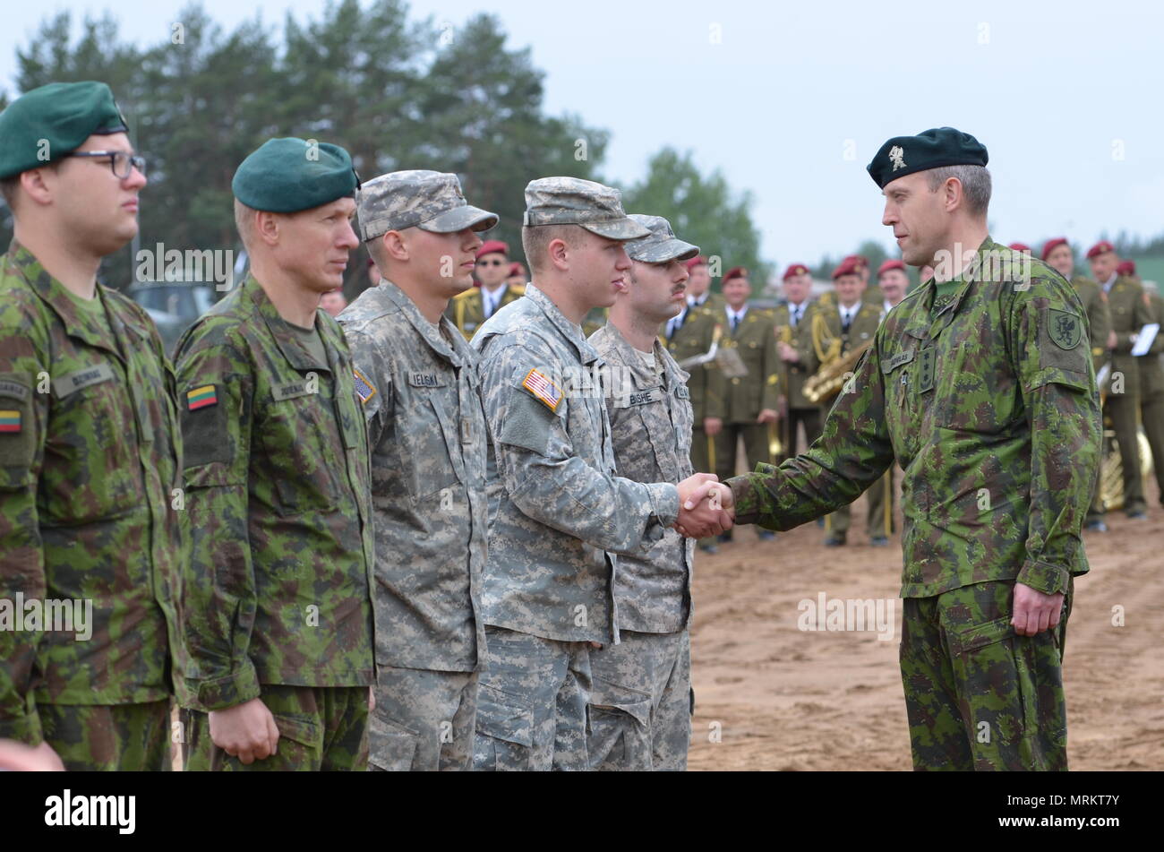 Three Soldiers, each from Lithuania Land Force and the United States Army  receive coins from Col. Arturas Radvilas, commander of Motorized Infantry  Brigade Griffin, Lithuanian Land Force, during the closing ceremony of