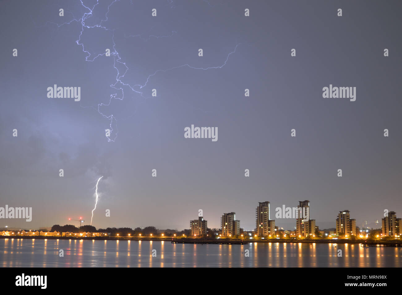 London, UK, 27th May 2018 Night time lightning storm seen over the River Thames in London on a Bank Holiday weekend with a bolt of lightning striking the ground near a block of flats –. Credit: A Christy/Alamy Live News. Stock Photo