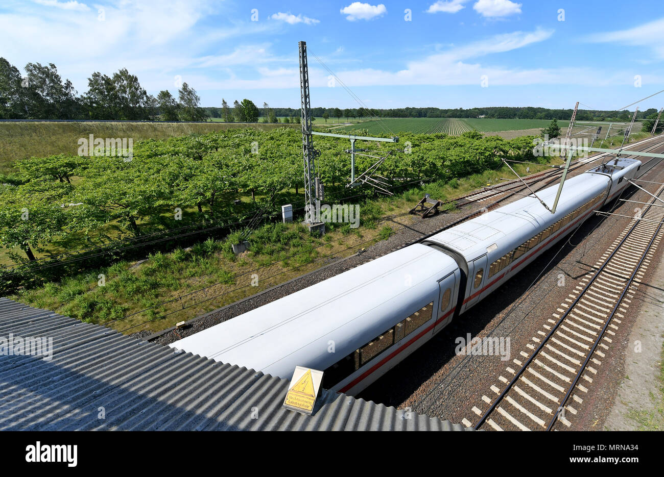 24 May 2018, Germany, Eschede: An Inter City Express (ICE) train passes the memorial site for the 1998 Eschede ICE derailment, where 101 cherry trees have been planted (C). On 3 June 1998, the ICE 884 'Wilhelm Conrad Roentgen' derailed on the Hannover-Hamburg route near the village of Eschede. 101 people died. Photo: Holger Hollemann/dpa Stock Photo