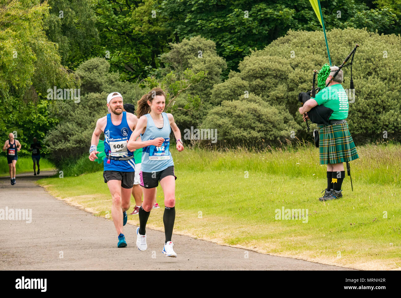 Edinburgh Marathon Festival, 26th May 2018. Gosford Estate, East Lothian, Scotland, UK. Tired male and female marathon runners at Mile 18. Josephine Stone, who was the fourth fastest woman in the race with Macmillan Cancer charity stand and man in kilt playing bagpipes Stock Photo
