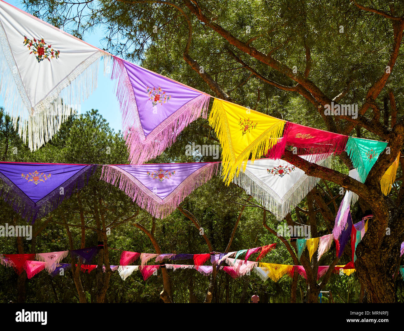 Trees dressed with colorful Mantones de Manila (Manila shawls) in a Flamenco fair. Spanish Yarn bombing. Stock Photo