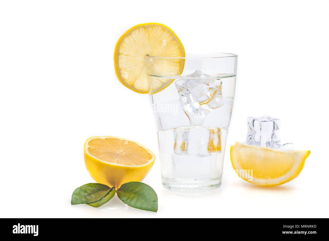 Water, lemon and ice cubes in a glass. Lemon slices and flax next to a