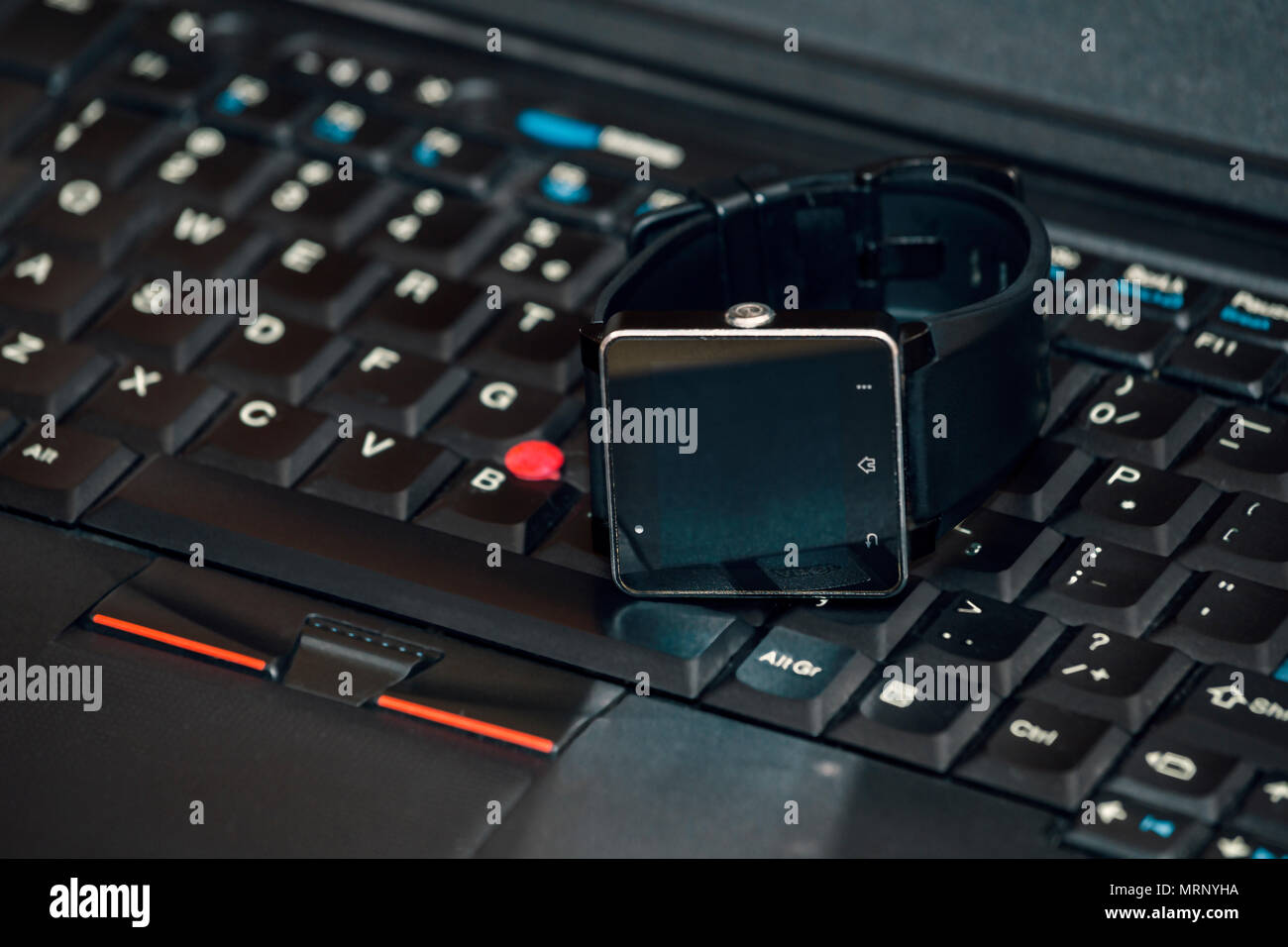 Smart wrist watch laying on a laptop keyboard. Abstract: always stay connected to internet and media. Stock Photo