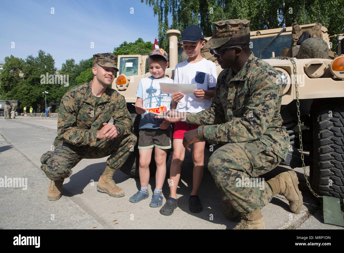 U.S. Marines with Marine Corps Forces Europe and Africa share Marine Corps stickers with Latvian children during a static display in Jelgava, Latvia, June 18, 2017. The event gave Marines the opportunity to meet with locals in the host country of Exercise Saber Strike 17, helping build stronger relationships with NATO Allies and partner nations beyond integrated training. (U.S. Marine Corps photo by Pfc. Sarah N. Petrock) Stock Photo