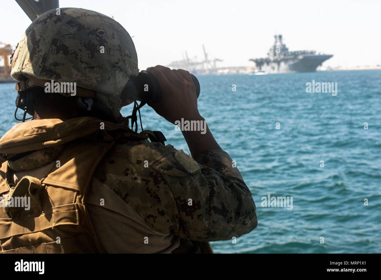 ARABIAN GULF (June 13, 2017) Operations Specialist 3rd Class Francisco Andresdiego, part of Coastal Riverine Squadron (CRS) 3, attached to Task Group (TG) 56.7, stands watch while providing a security escort for the amphibious assault ship USS Bataan (LHD 5) as it departs from Jebel Ali, United Arab Emirates June 13. The ship and its ready group are deployed in the U.S. 5th Fleet area of operations in support of maritime security operations  to reassure allies and partners, and preserve the freedom of navigation and the free flow of commerce in the region. (U.S. Navy photo by Mass Communicatio Stock Photo