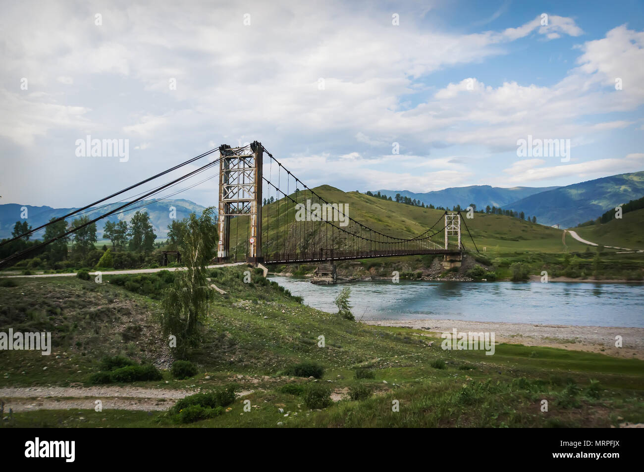 wooden suspension bridge over a mountain river high in the mountains of Altai. Stock Photo
