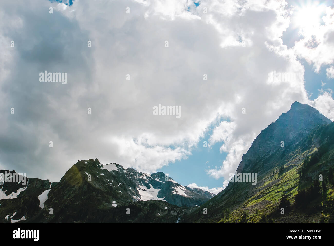 a big white cloud in the natural landscape with the tops of the mountains. Stock Photo