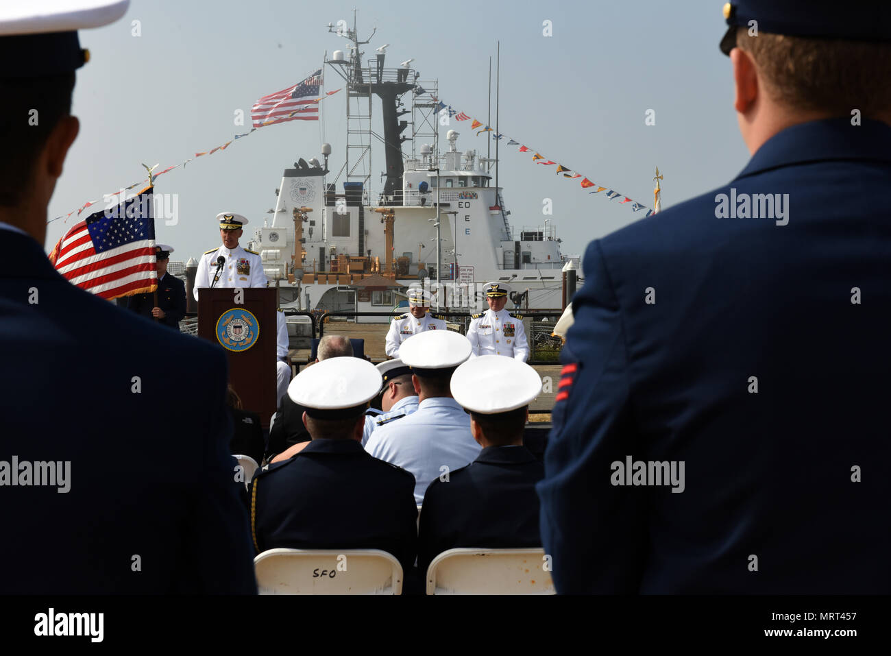 The Coast Guard Cutter Active sits in the background during a change-of-command ceremony held at Air Station Port Angeles, Washington, June 30, 2017. The Active crew conducts various missions including law enforcement, defense readiness and search and rescue in an operating area spanning from South America to the Washington coast. U.S. Coast Guard photo by Petty Officer 2nd Class Ali Flockerzi. Stock Photo