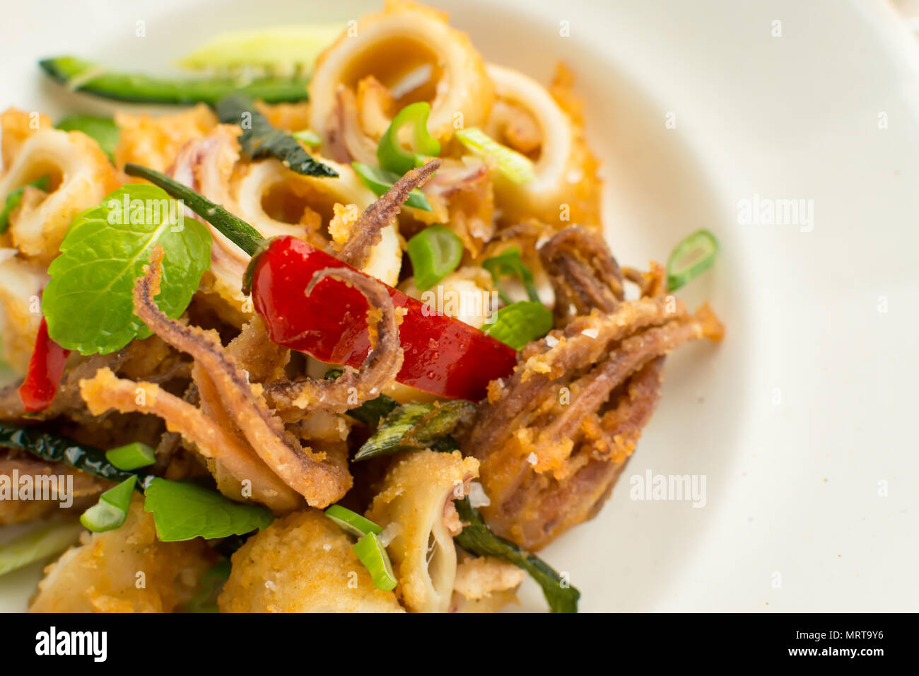 Fresh Fried Squids, Chili Pepper and Mint Leaves on White Plate Stock Photo