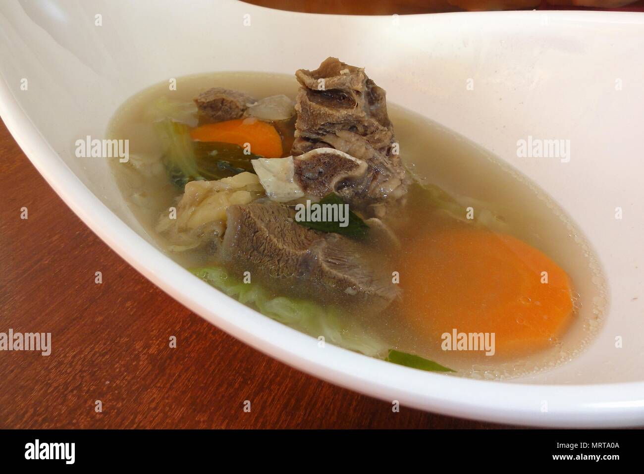 Beef bone soup with cabbage and onions served in a deep white bowl. It